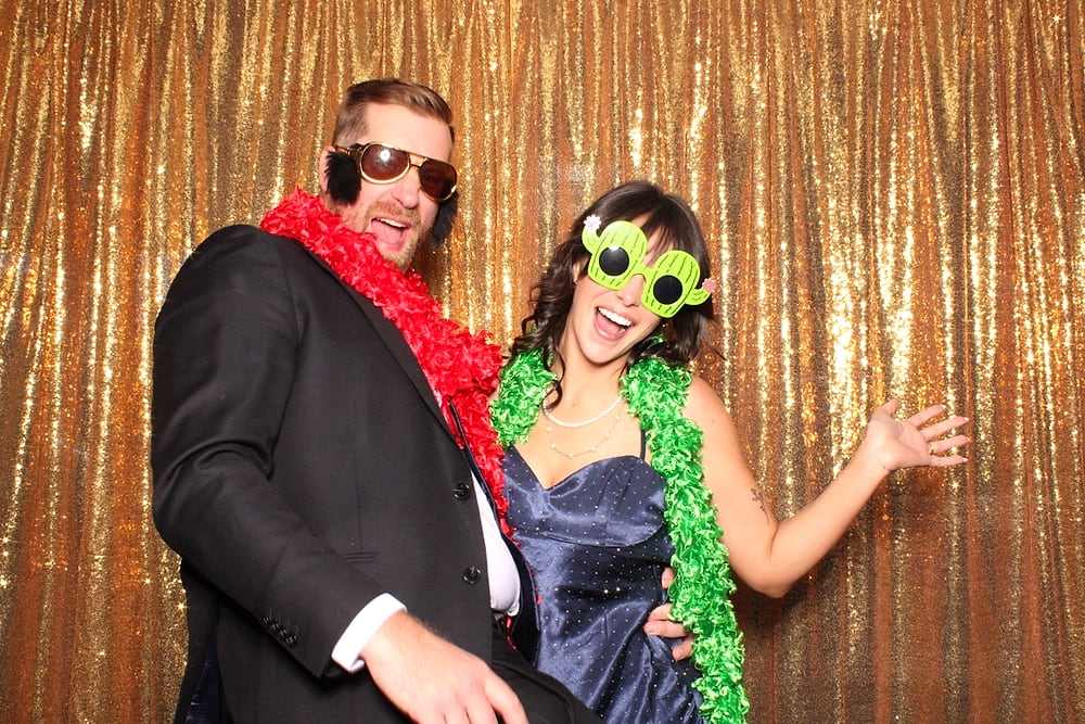Couple in feather boas and prop glasses at an Austin wedding photo booth