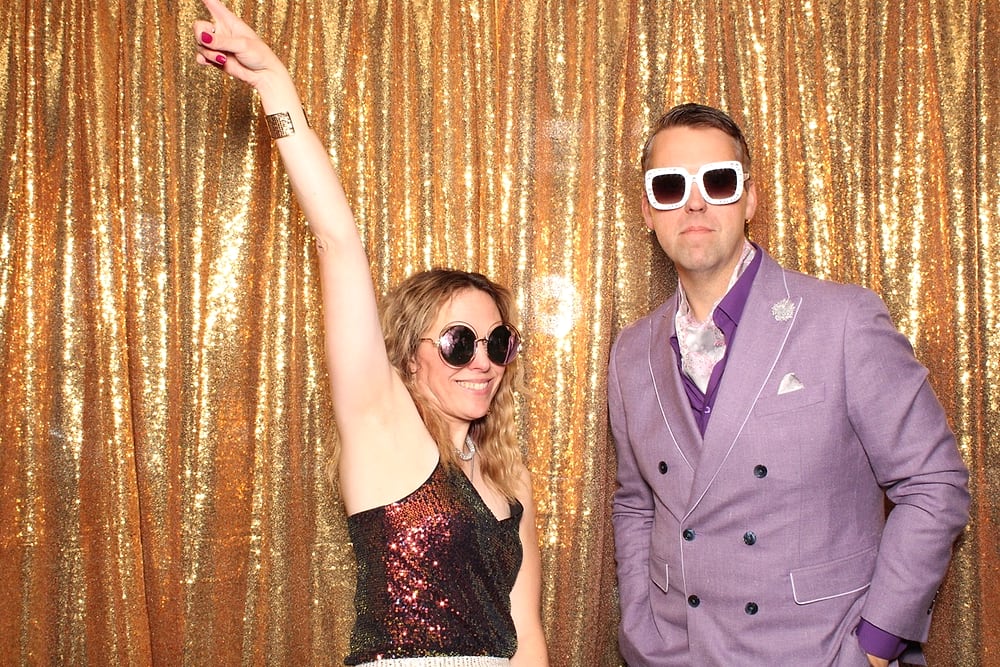Couple striking a pose at the Posed photo booth, gold sequin backdrop, Austin wedding