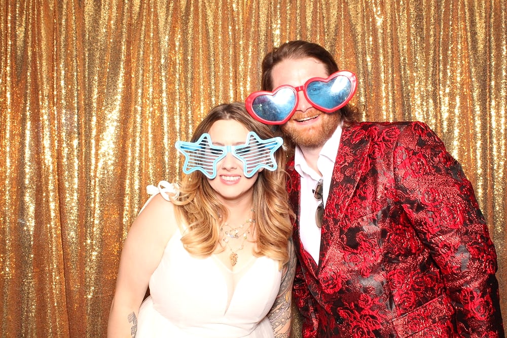 Couple in oversized sequin glasses at an Austin wedding photo booth